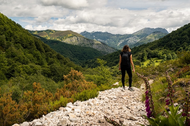 Jonge vrouw die het uitzicht op de hooglanden bewondert tijdens een wandeling in Asturië