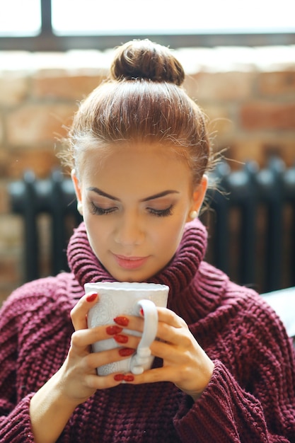 Gratis foto jonge vrouw die hete thee op de bank drinkt