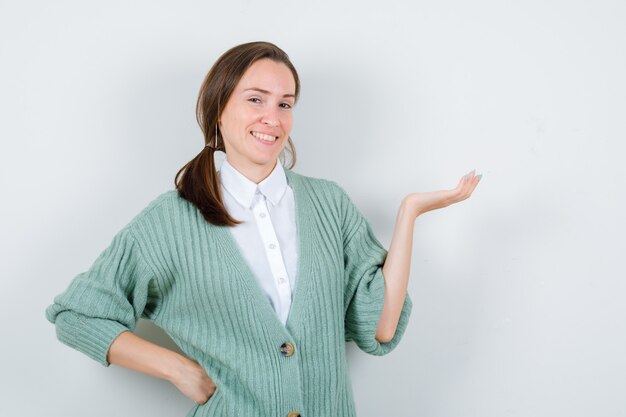 Jonge vrouw die iets op een witte muur toont of presenteert met kopieerruimte