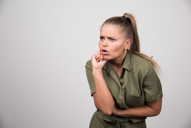 Jonge vrouw die iets op grijze muur bekijkt.