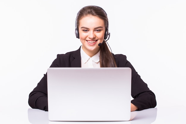 Jonge vrouw die in bureau met laptop en hoofdtelefoons op witte muur, klantenservice en call centre werkt.