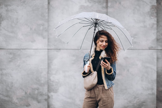 Jonge vrouw die in de regen met paraplu loopt