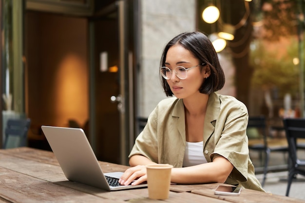 Jonge vrouw die in een café werkt met een laptop en koffie drinkt Aziatische studente met computer stud
