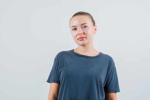 Jonge vrouw die in grijs t-shirt kijkt en positief kijkt