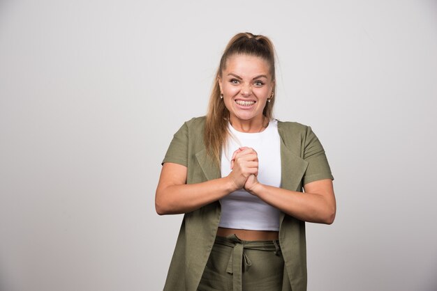 Jonge vrouw die in groen overhemd haar handen houdt.