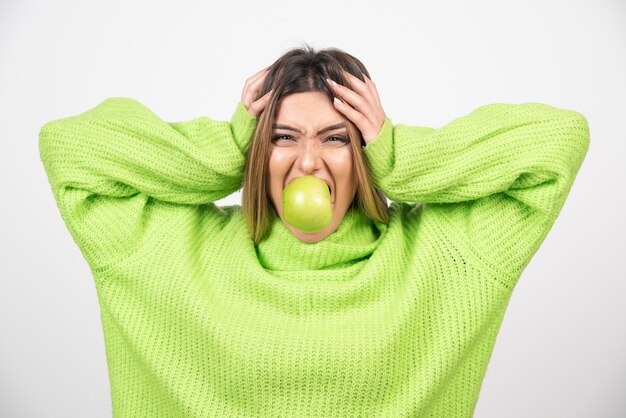 Gratis foto jonge vrouw die in groene t-shirt een appel eet.