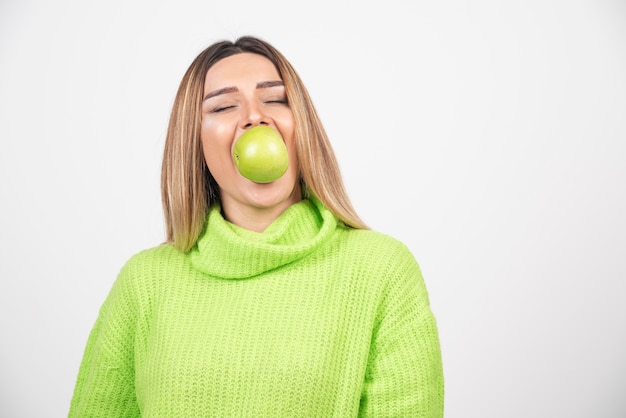 Jonge vrouw die in groene t-shirt een appel eet