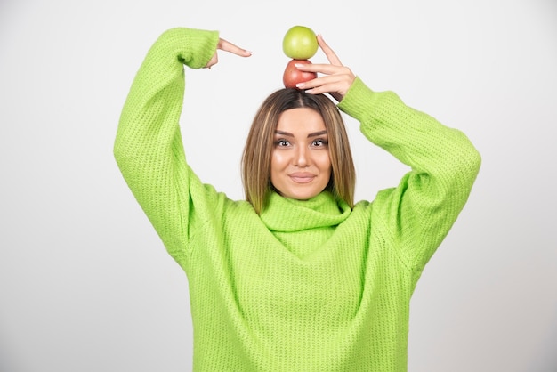 Jonge vrouw die in groene t-shirt twee appels boven houdt.