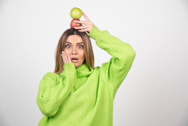 Jonge vrouw die in groene t-shirt twee appels boven houdt.