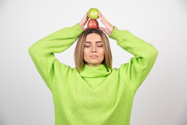 Jonge vrouw die in groene t-shirt twee appels boven houdt.