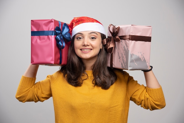 Gratis foto jonge vrouw die in kerstmanhoed de dozen van de handengift houden.