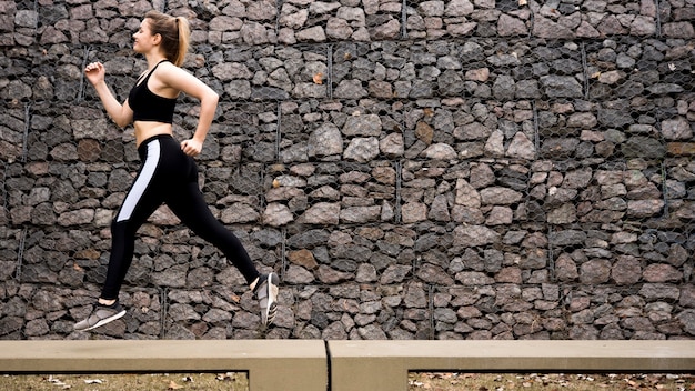 Jonge vrouw die in openlucht met sportkleding loopt