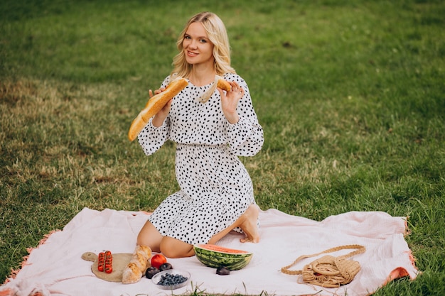 Jonge vrouw die in park stokbrood eet