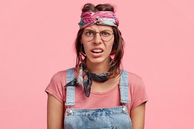 Gratis foto jonge vrouw die kleurrijke hoofdband en denimoveralls draagt