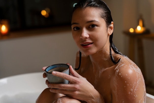 Gratis foto jonge vrouw die koffie drinkt terwijl ze een bad neemt