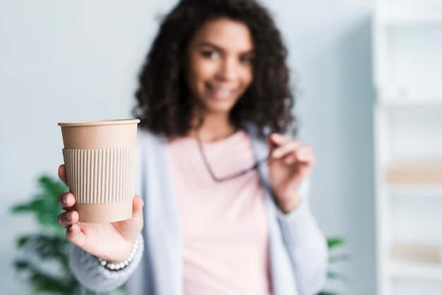 Jonge vrouw die koffie op het werk aanbiedt te drinken