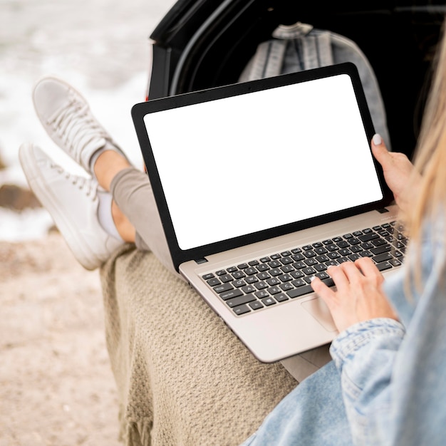 Gratis foto jonge vrouw die laptop op road trip doorbladert