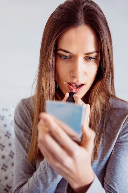 Jonge vrouw die lippenstift toepast