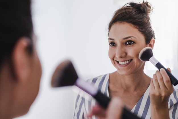 Jonge vrouw die make-up opdoet voor de spiegel