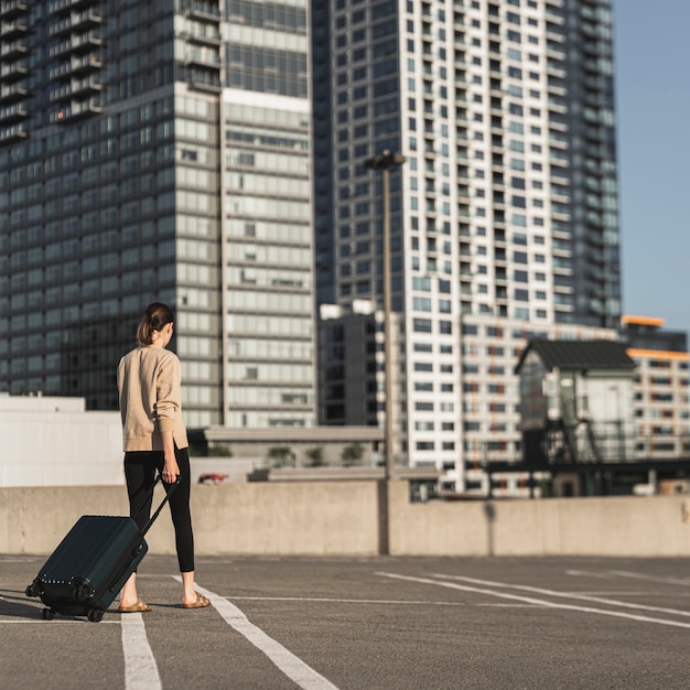 Gratis foto jonge vrouw die met een koffer in de stad loopt