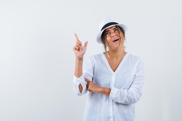 Jonge vrouw die met haar vinger op witte achtergrond verschijnt