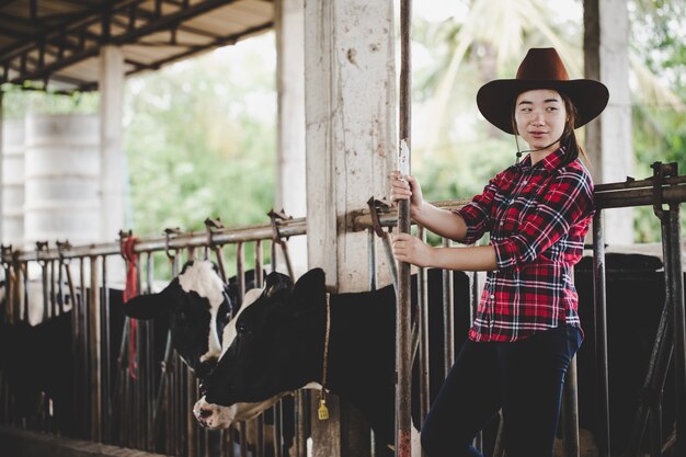 Jonge vrouw die met hooi voor koeien op melkveehouderij werkt