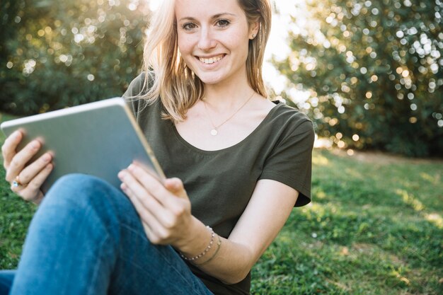 Jonge vrouw die met tablet camera bekijkt