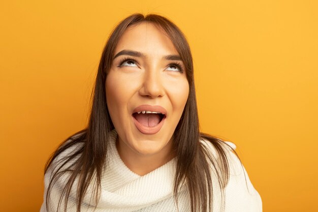 Jonge vrouw die met witte sjaal gelukkig en vrolijk omhoog kijkt