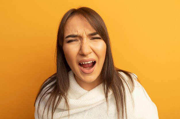 Jonge vrouw die met witte sjaal met geïrriteerde uitdrukking schreeuwt