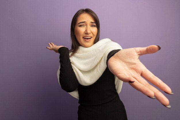 Jonge vrouw die met witte sjaal met uit wapen glimlacht