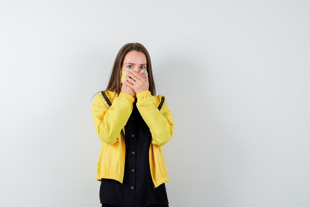 Jonge vrouw die mond bedekt met handen