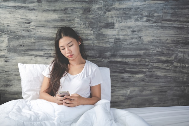 Jonge vrouw die net wakker werd en een telefoon vasthield