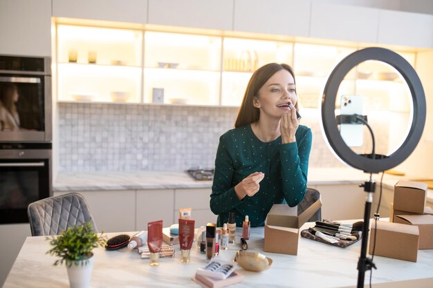 Jonge vrouw die nieuwe lipgloss demonstreert en er opgewonden uitziet