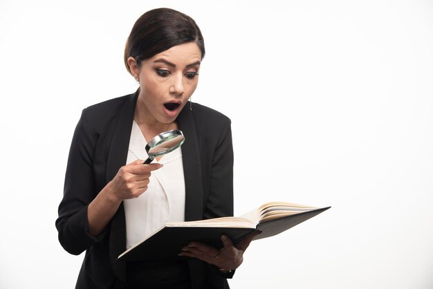 Jonge vrouw die notitieboekje met vergrootglas bekijkt. Hoge kwaliteit foto