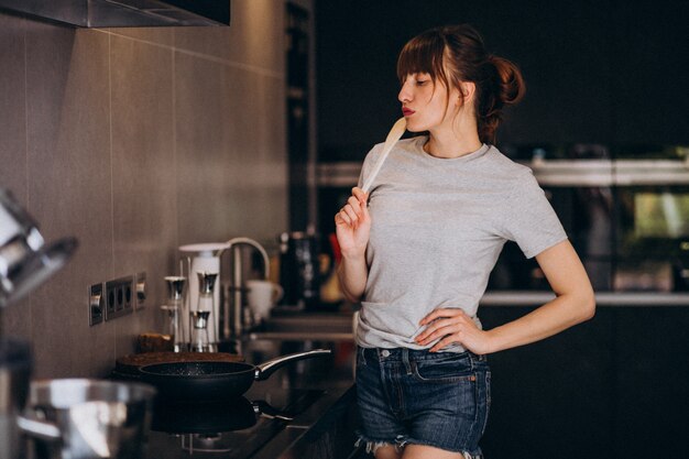 Jonge vrouw die ontbijt in keuken in de ochtend voorbereidt