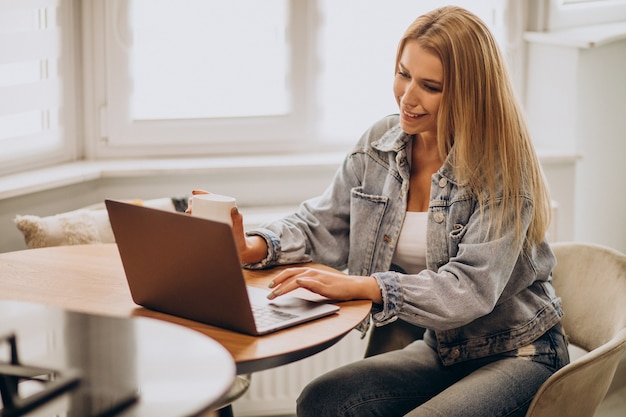 Jonge vrouw die op computer van huis werkt