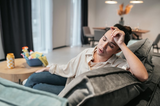 Jonge vrouw die op de bank zit en er moe uitziet