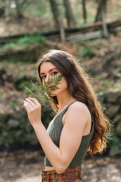 Jonge vrouw die op een blad in bos ruikt