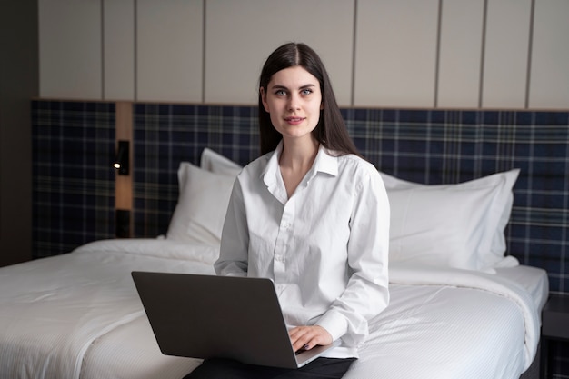 Gratis foto jonge vrouw die op haar laptop in een hotelkamer werkt