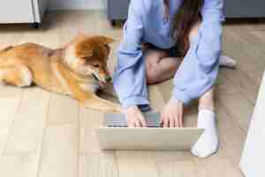 Gratis foto jonge vrouw die op haar laptop werkt naast haar hond