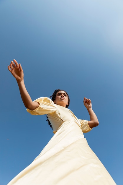 Gratis foto jonge vrouw die op hemelachtergrond danst