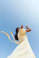 Gratis foto jonge vrouw die op hemelachtergrond danst