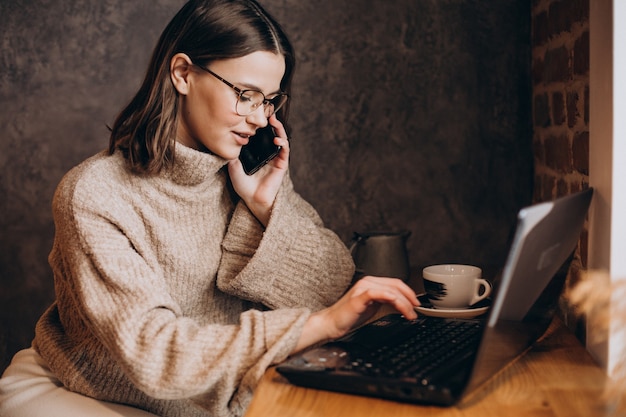 Jonge vrouw die op laptop in een café werkt