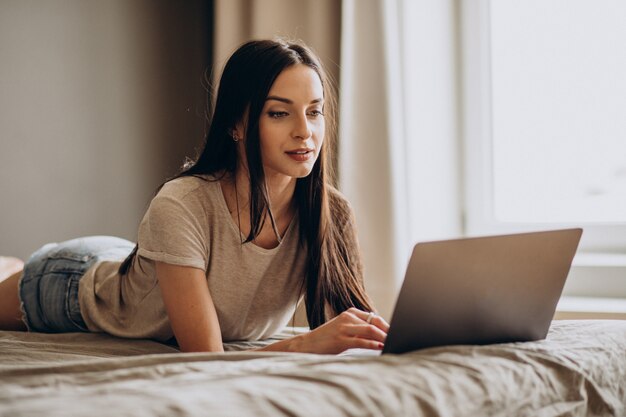 Jonge vrouw die op laptop van huis werkt