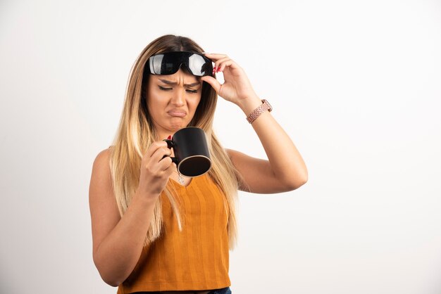 Jonge vrouw die op zwarte kop kijkt en beschermende brillen draagt.