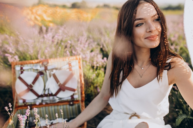 Gratis foto jonge vrouw die picknick op een lavendelgebied heeft