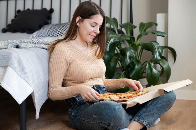 Jonge vrouw die pizza thuis eet