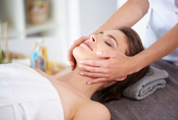 Jonge vrouw die professionele gezichtsmassage krijgt