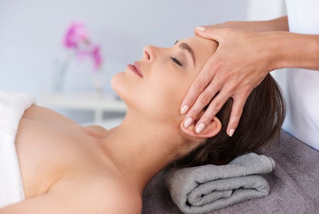 Jonge vrouw die professionele gezichtsmassage krijgt