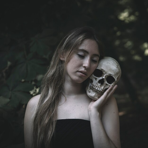 Jonge vrouw die schedel in hout omhelst